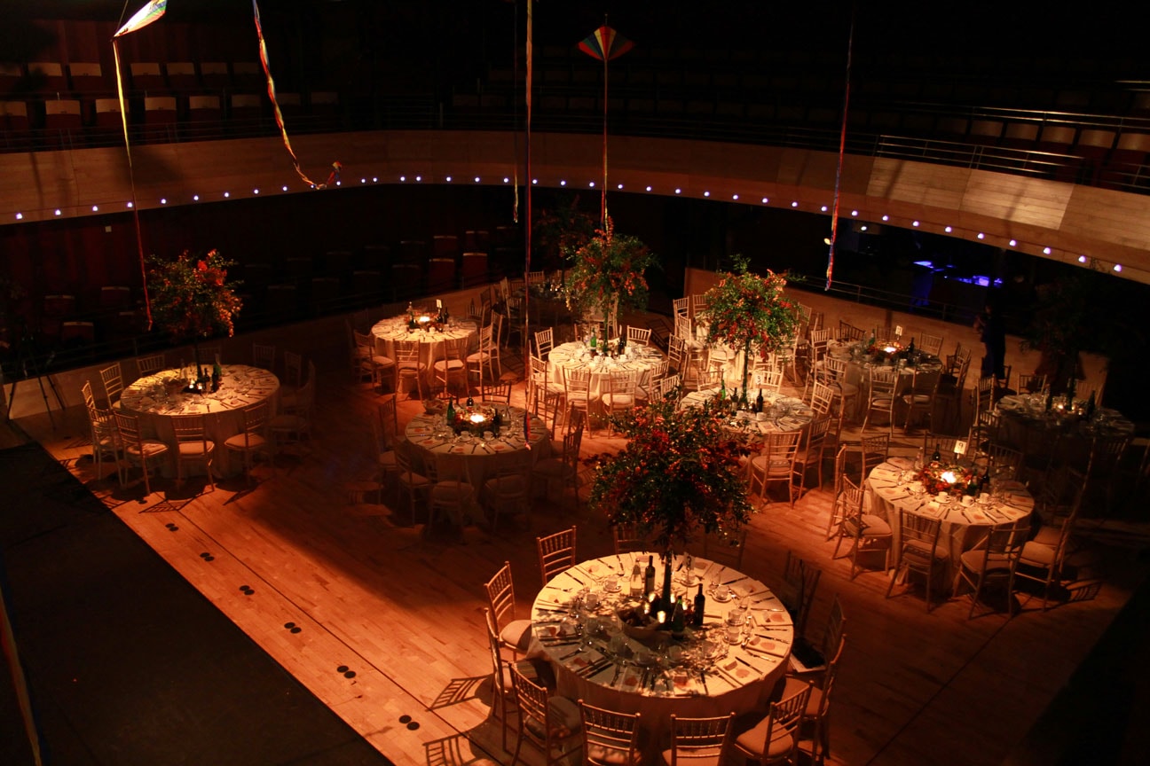 The Pentland Theatre set for a banquet, pictured from above. 8 round tables can be seen, with white tablecloths and autumnal flowers.