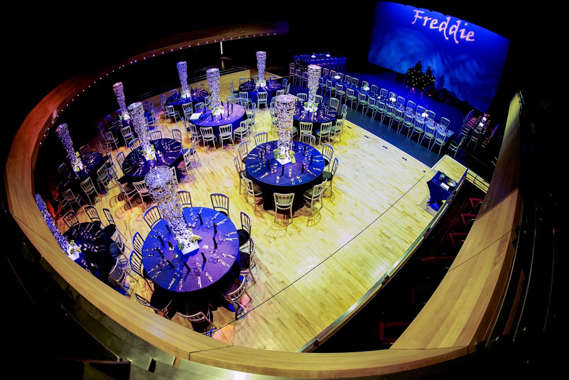 The Pentland Theatre set for a banquet, pictured from above, with round tables with black table cloths and large silver table centre decorations