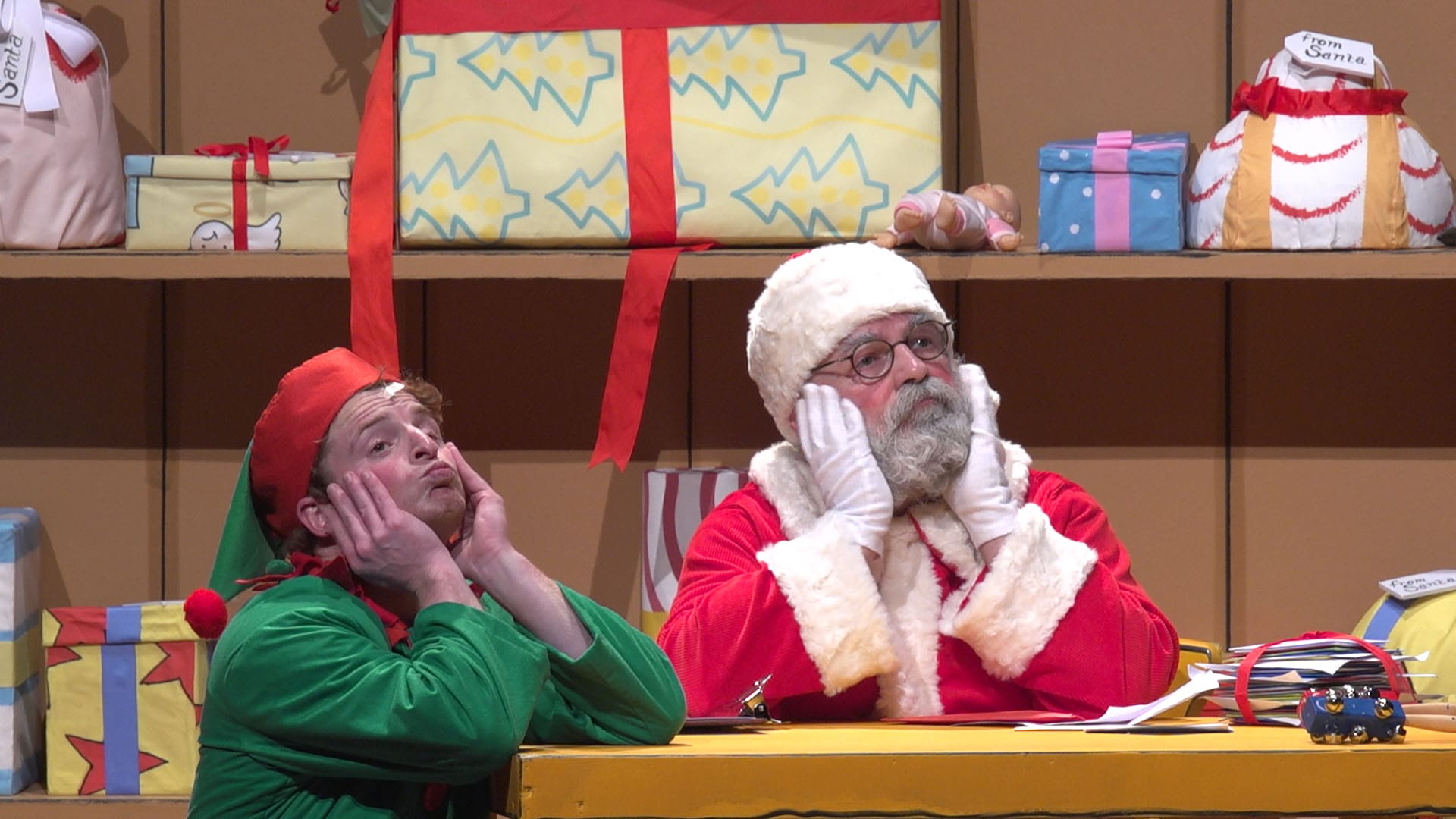 Santa and an elf sit with the heads in the hands