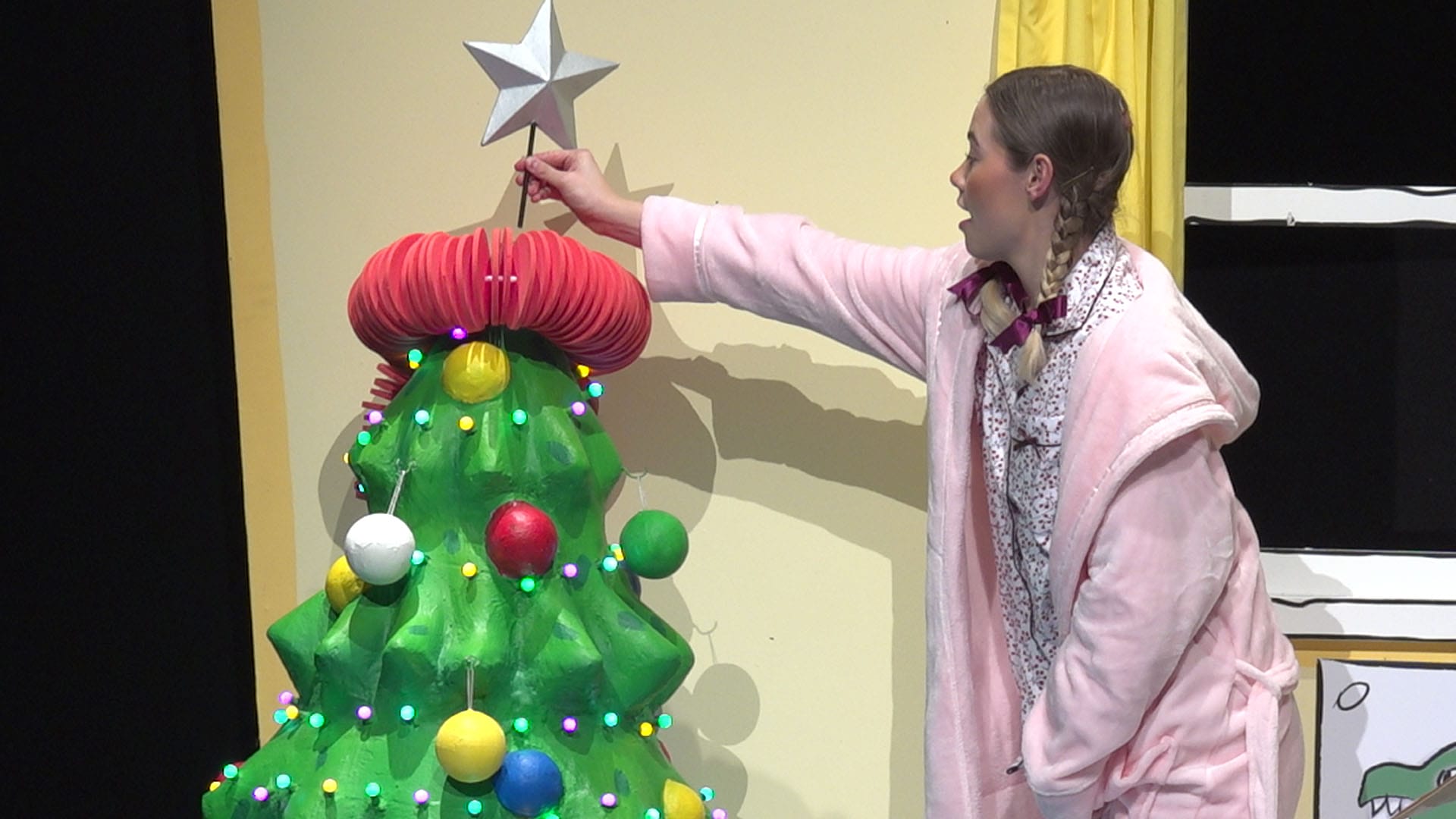 A girl puts the star on top of the Christmas three
