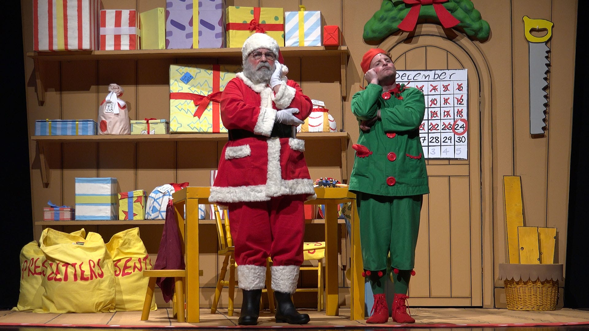 Santa and an elf stand in santas workshop