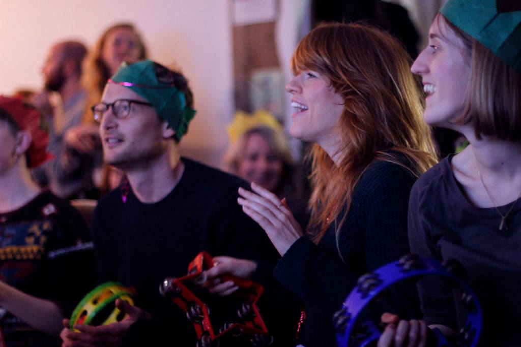 Audience members watching Karolaoke wearing Christmas hats.