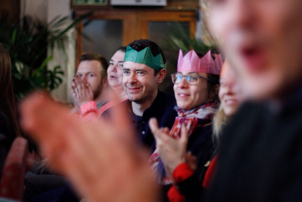 Audience members watching Karolaoke wearing Christmas hats