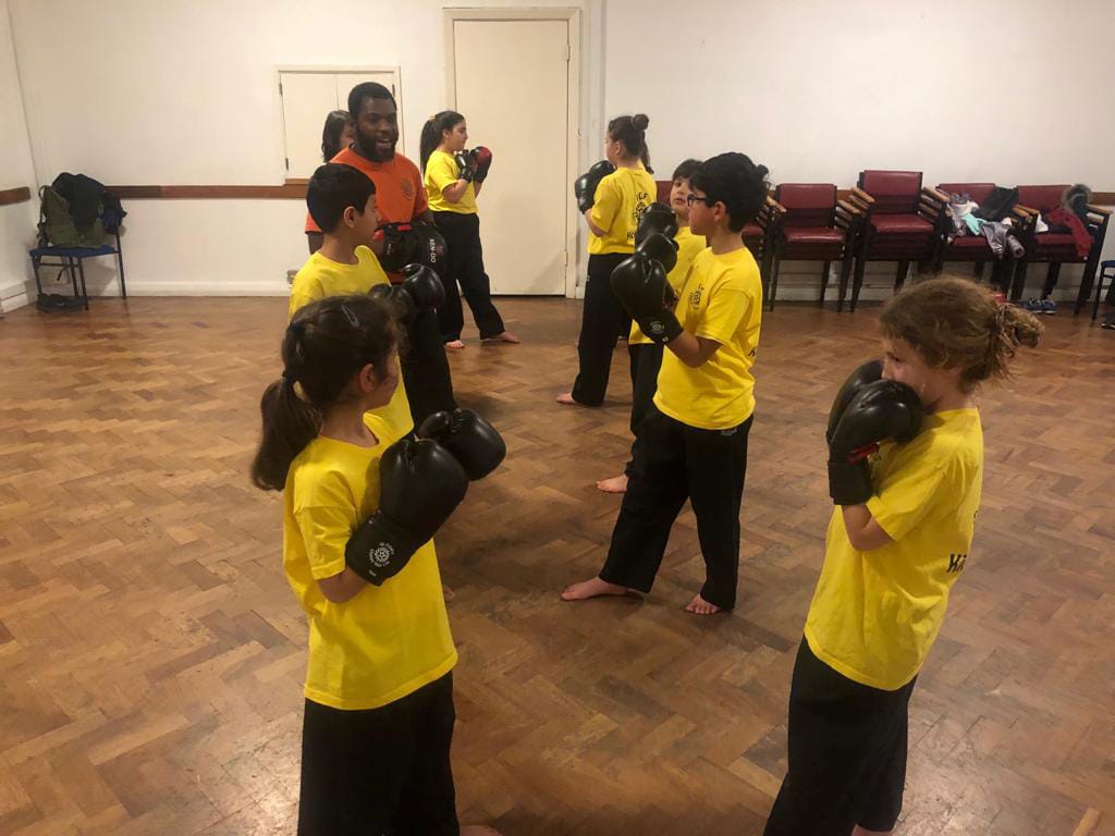 A group of young people in a studio being taught kickboxing by an instructor