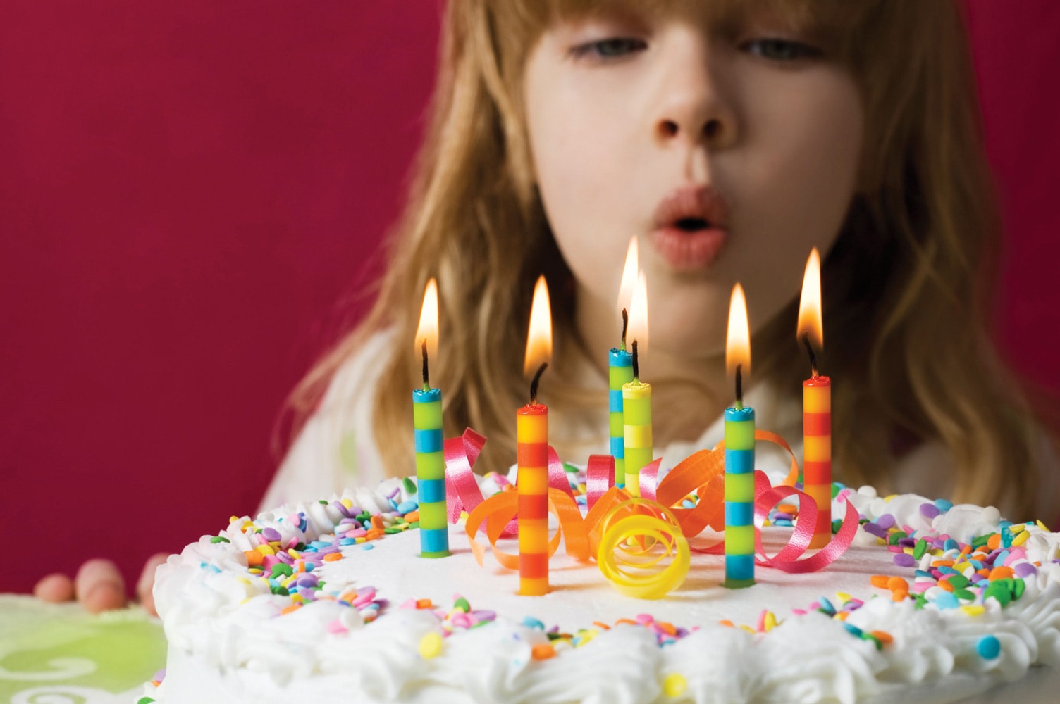 A child blows out birthday candles on a cake