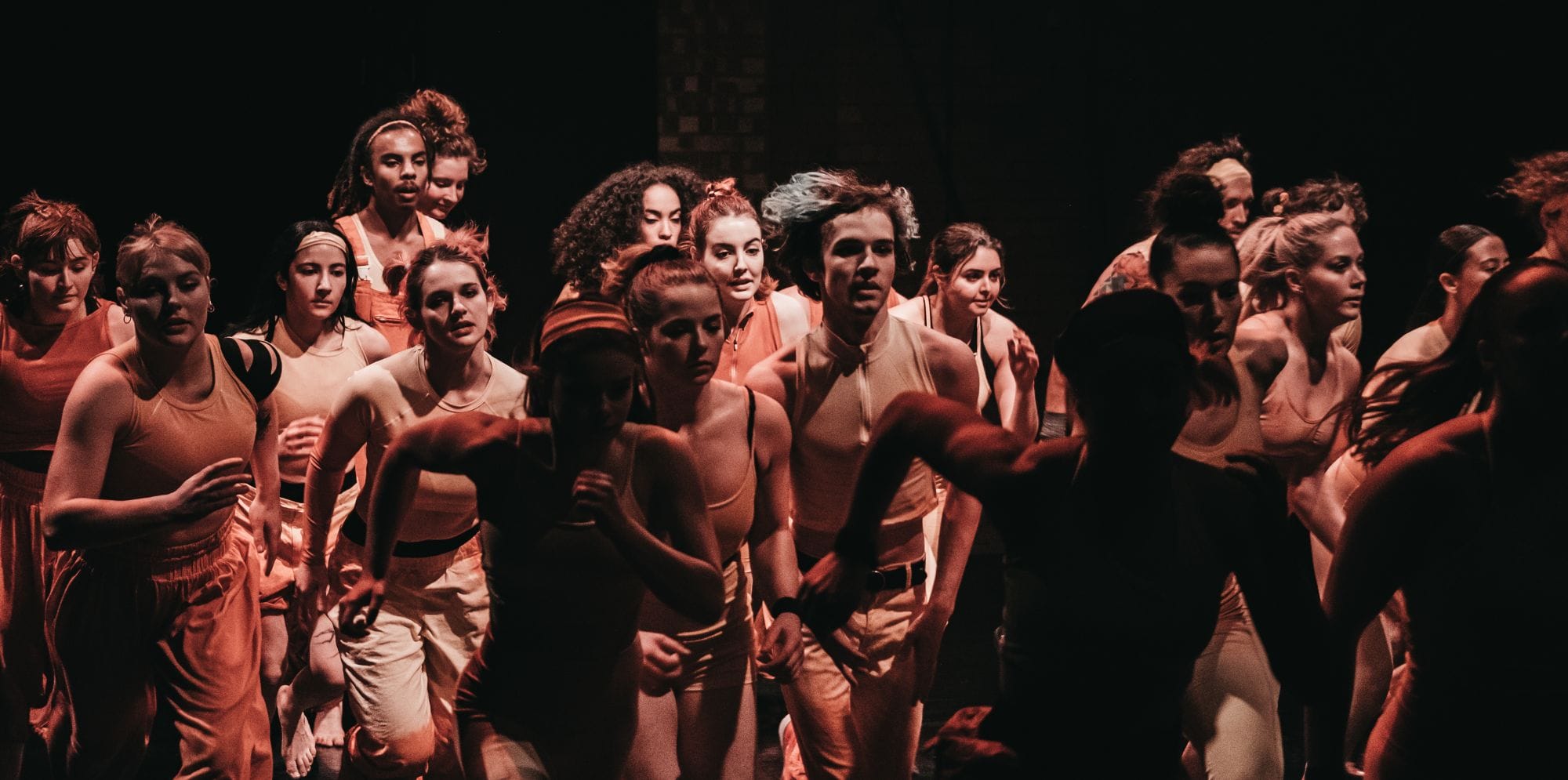 Diverse group of performers wearing similar clothing jog past