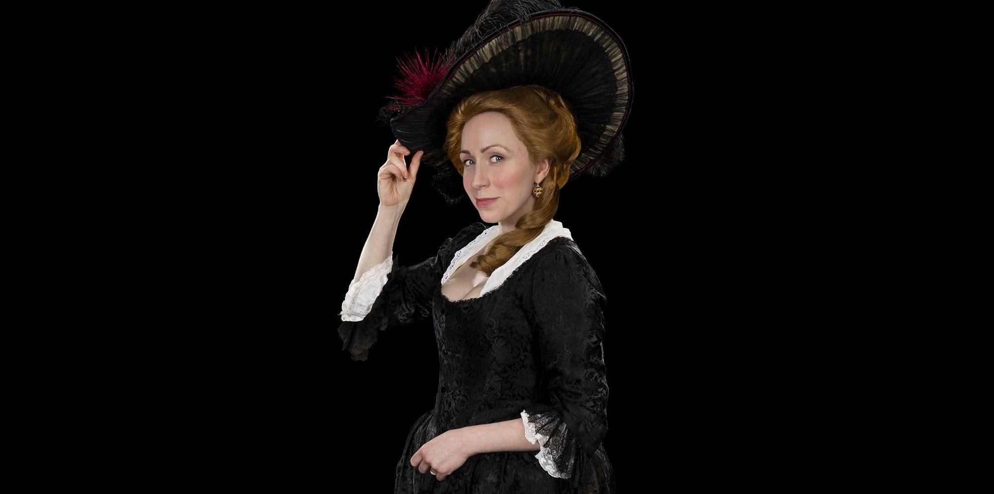 A women wears an 1800's style black dress and hat
