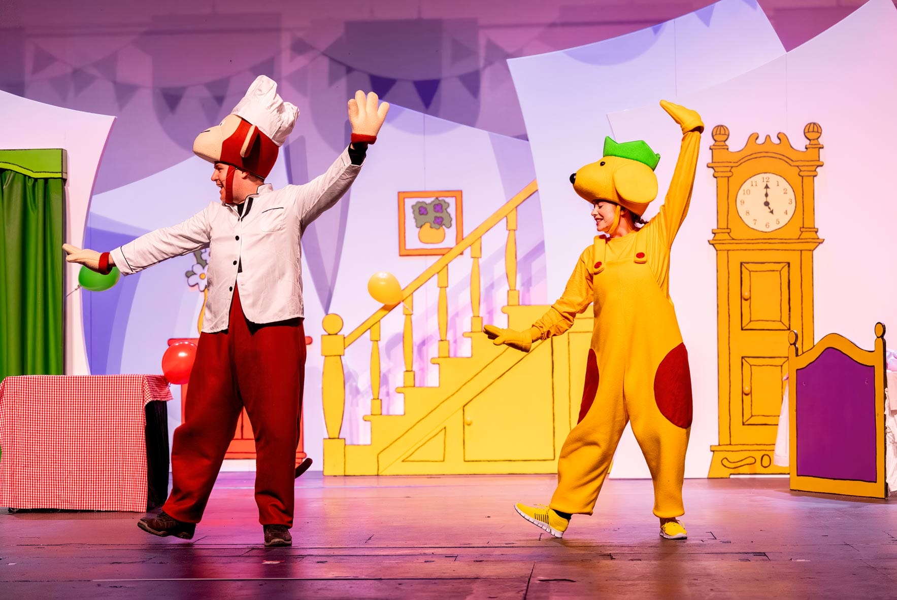 Spot and a man in a red hat are dancing on the stage.