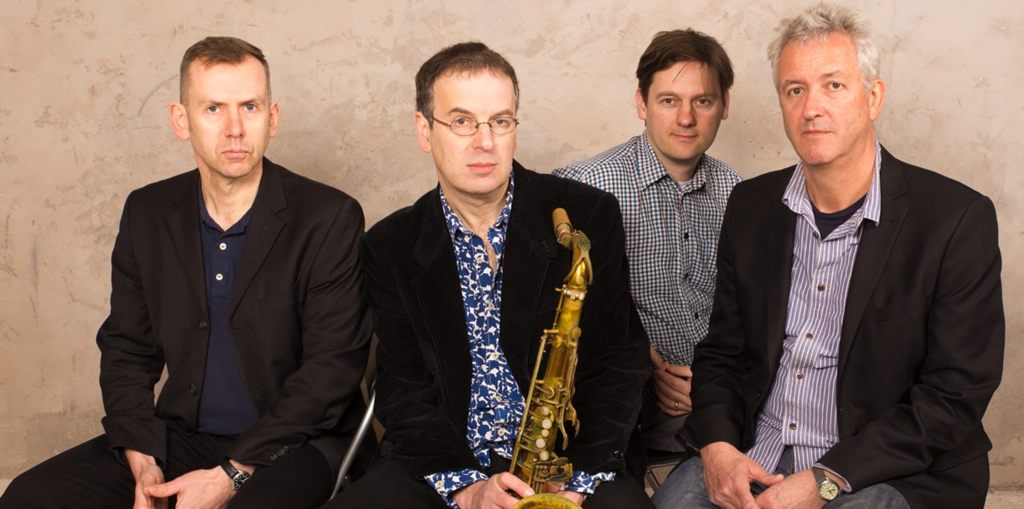 The Theo Travis Music group sit, one is holding a saxaphone