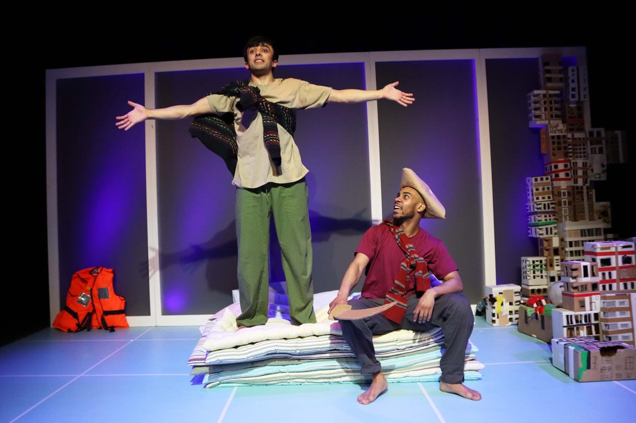 One of the male characters look like a captain wearing a carboard hat and holding a sword. The other making a big speech standing on the mattresses.