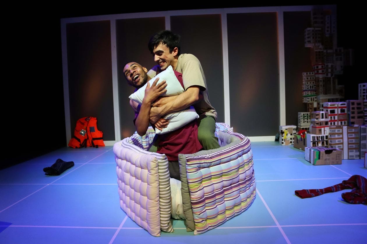 The two male characters are being playful in the boat they made out of their mattresses.
