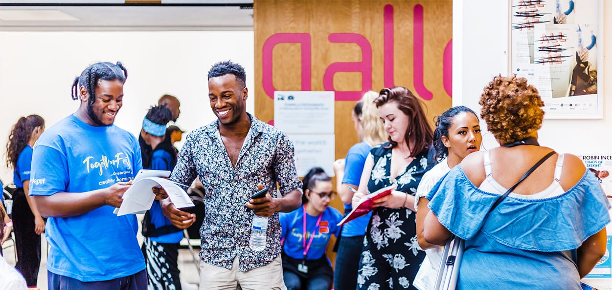 A group of adults smiling and talking at an artsdepot community event.