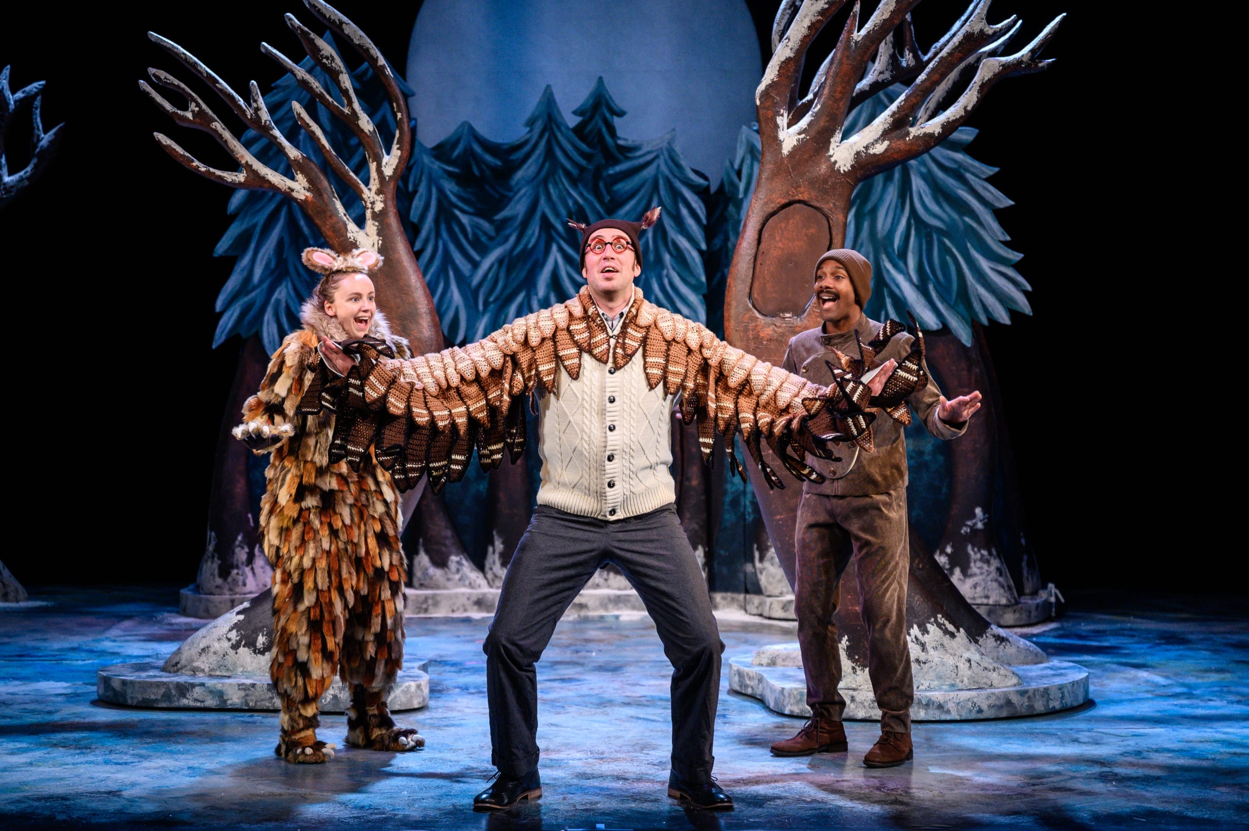 Production shot from The Gruffalo's Child artsdepot! The Gruffalo's Child, Owl and mouse stand together in a line, with Owl in the middle with glasses, outstretched wings, and a whimsical expression.