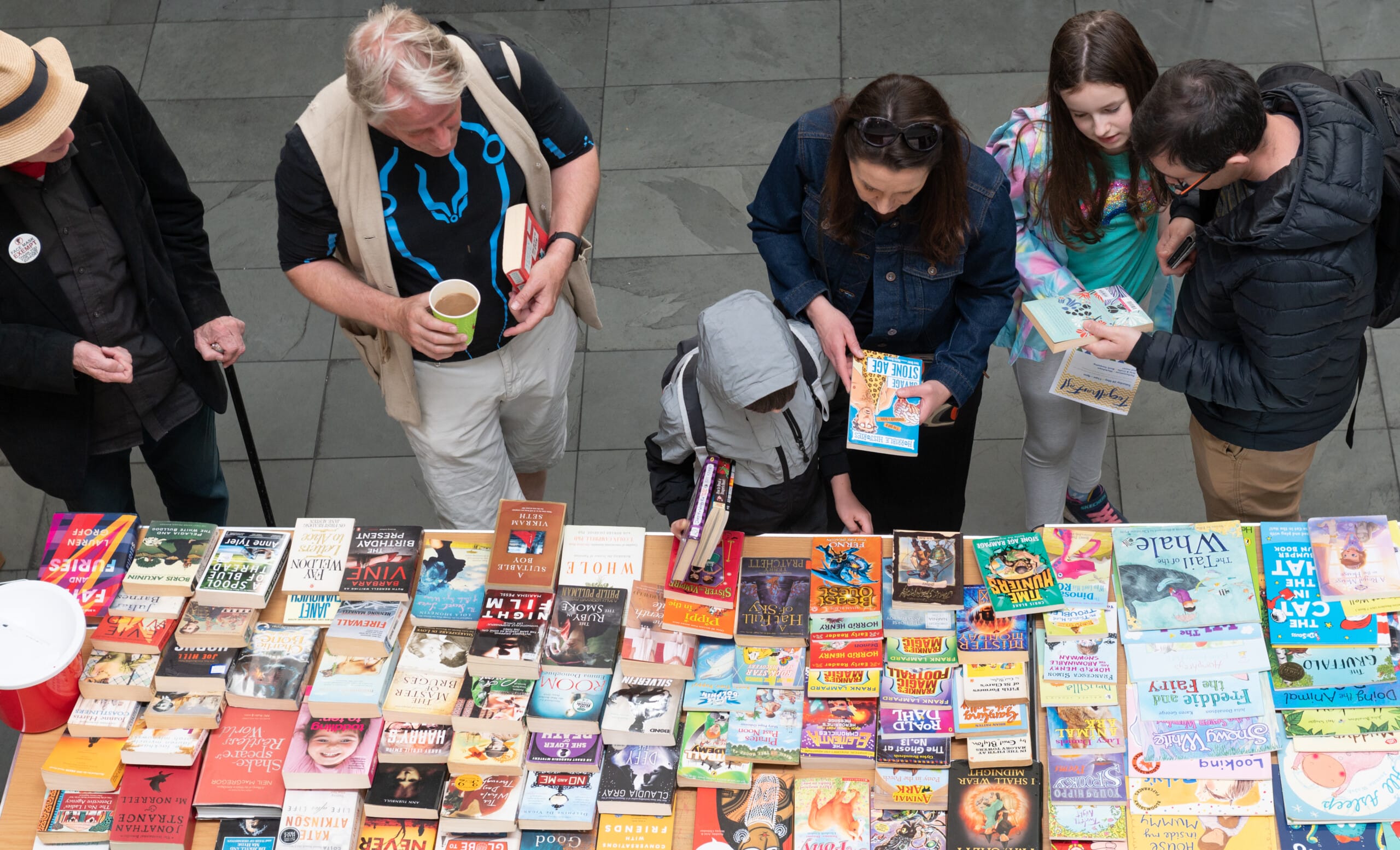 A birds-eye view of artsdepot visitors browsing a colourful table covered with lots of children's books.
