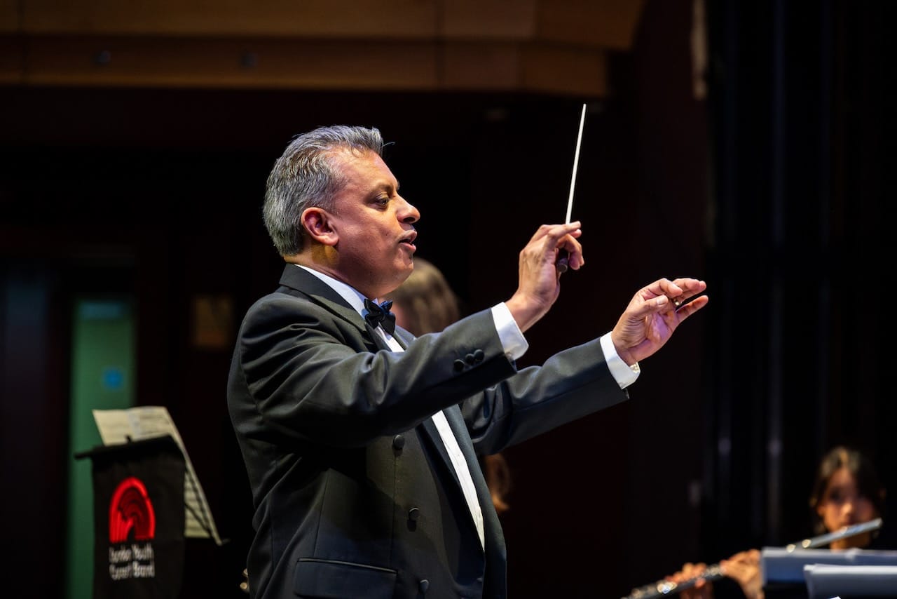 Close up photograph of London Youth Concert band conductor in action.