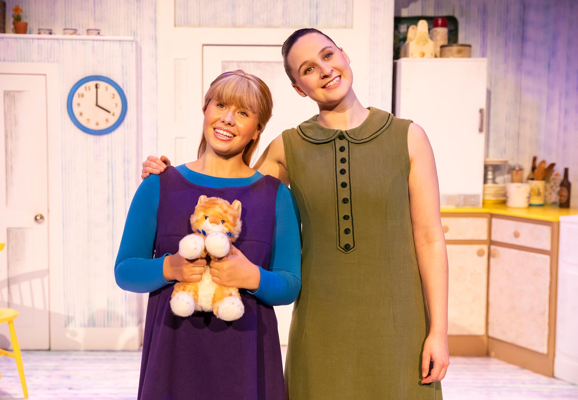 The characters Sophie and Mummy on stage in The Tiger Who Came to Tea. Sophie is holding a cuddly toy tiger. Mummy has her arm around her.