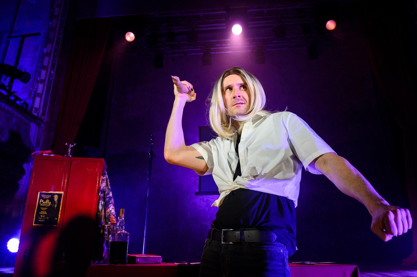 The Spike character wearing a blond wig holds up a prop finger looking suspicious.