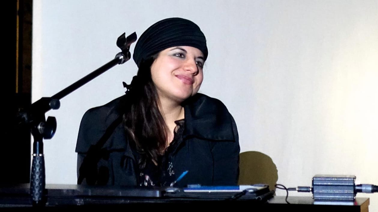 An image of Roshi Nasehi on stage sitting behind a desk.