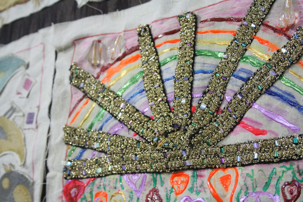 A close up of an embroidered patchwork showing a golden sunburst shape.