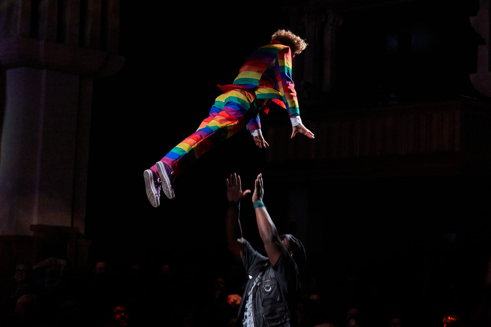 A performer in Showdown flies through the air into the open arms of another performer.