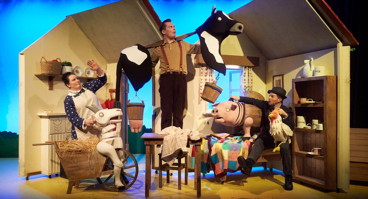 A Squash and A Squeeze production still. Actors interact with animal puppets in a rural cottage setting on stage.
