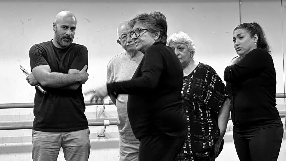 A black and white image of a group of people rehearsing in a studio.