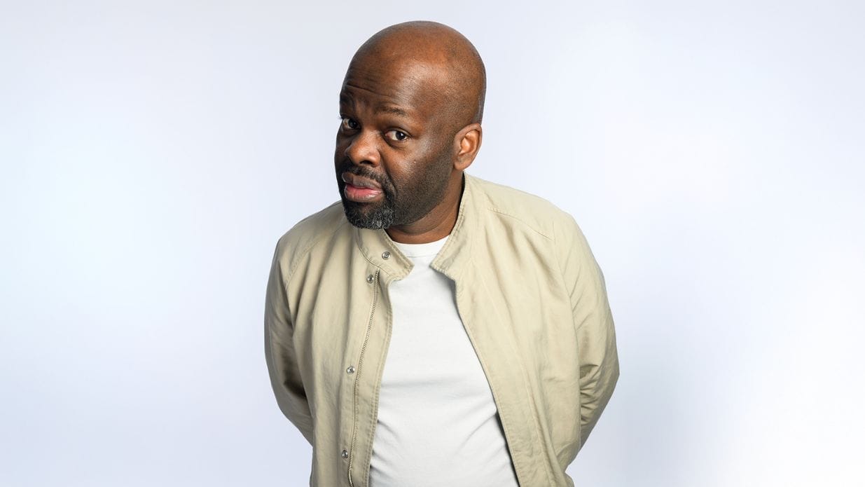 Comedian Daliso Chaponda poses in front of a white background.