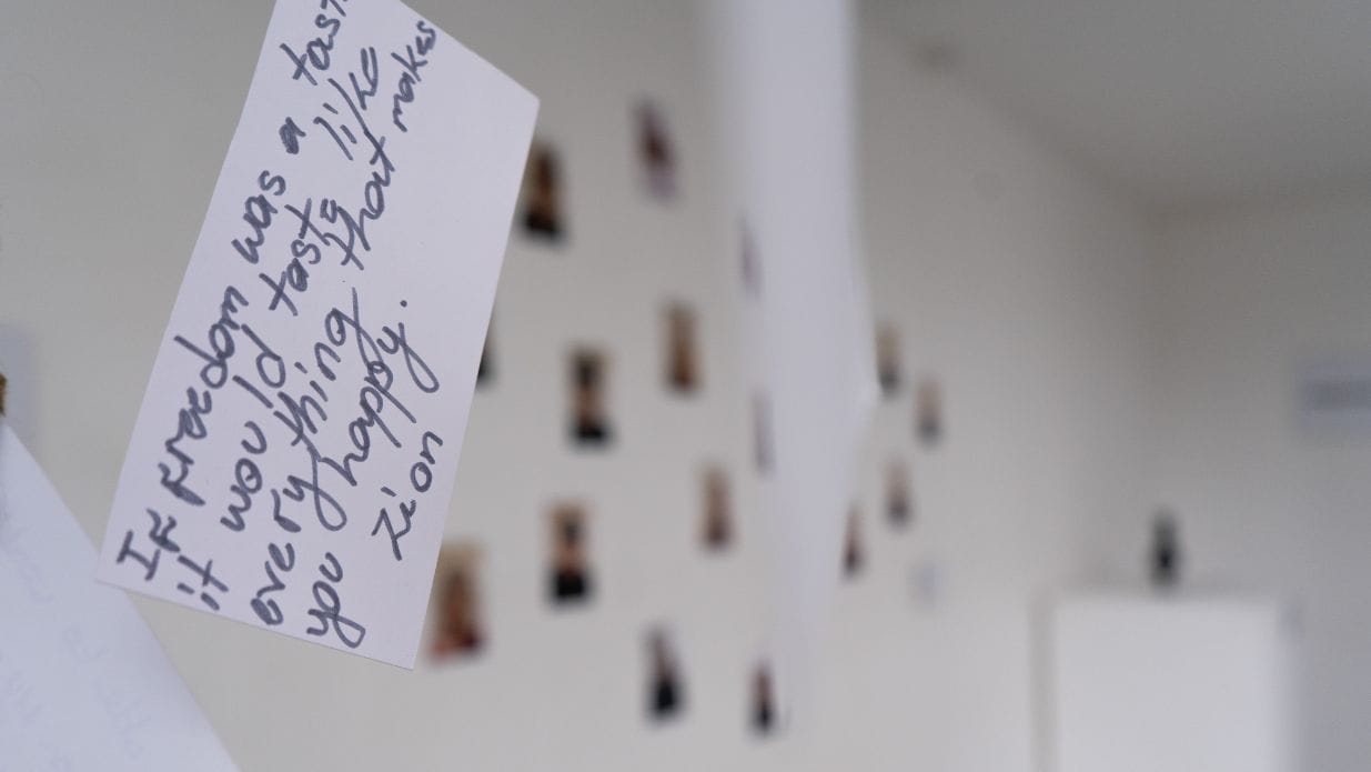 A small white piece of card hangs in the foreground. Written in black on the card is 'If freedom was a taste it would taste like everything that makes you happy - Zion'