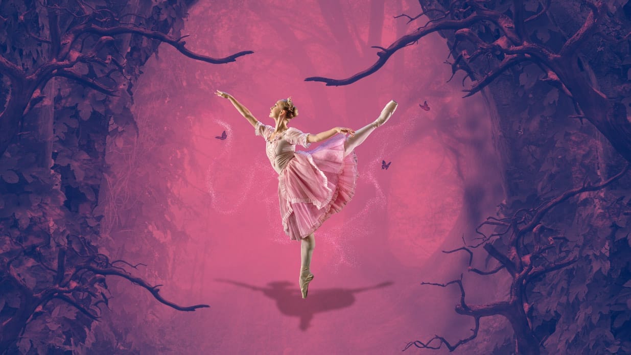 A ballerina in a pink dress stands on pointe in front of a background in pink and purple which looks like a shadowy forest.